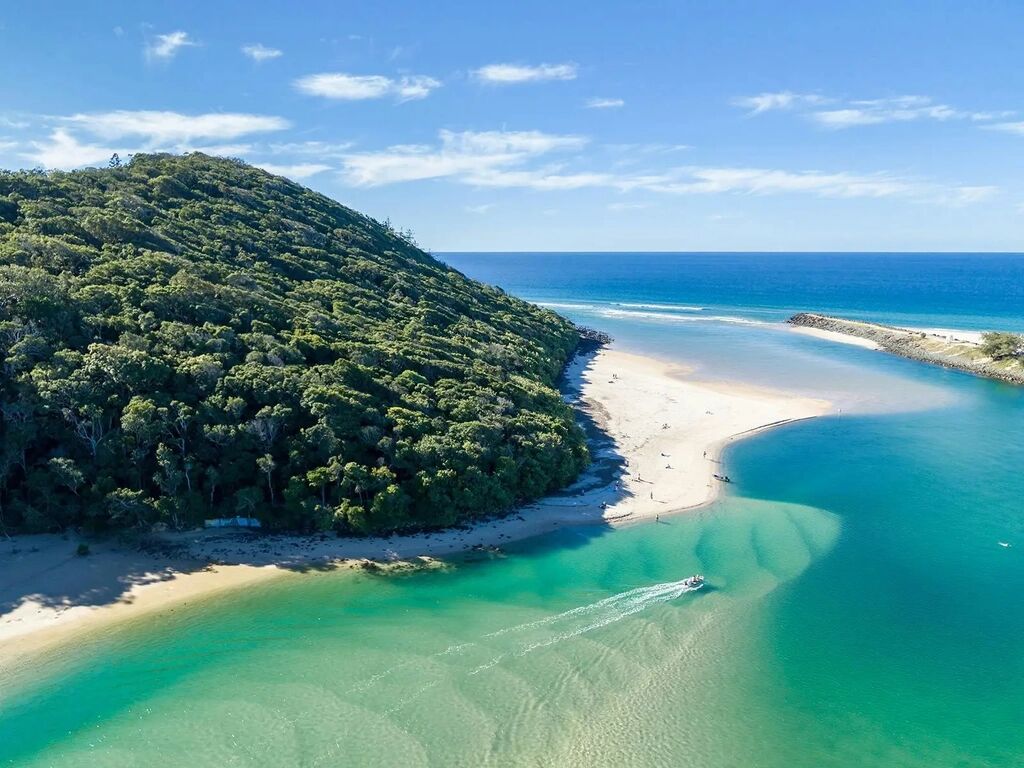 Gold Coast holiday views over Tallebudgera Creek, with turquoise water winding past a sandbar into the ocean beside the Burleigh Headland